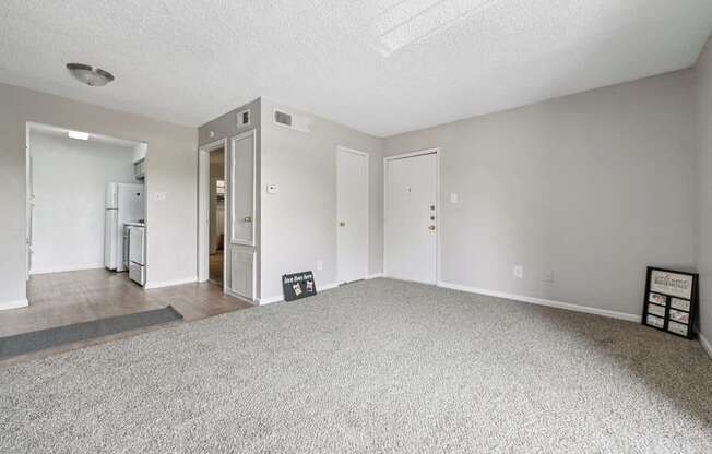A room with a carpeted floor and a fridge in the corner.