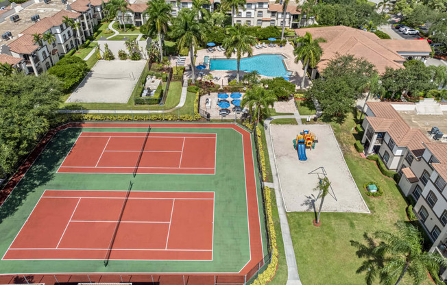 an aerial view of a tennis court with a pool and trees