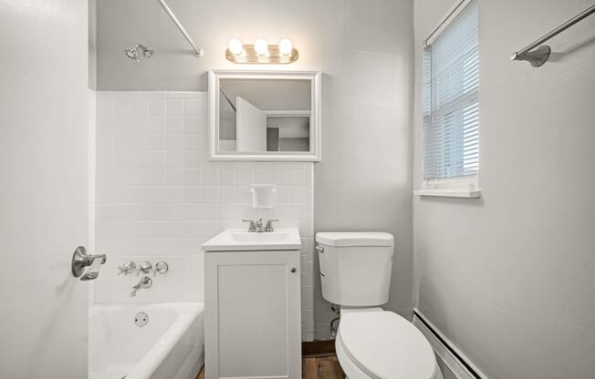a bathroom with a toilet sink and tub and a mirror