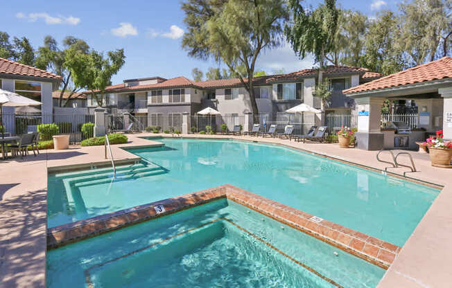 A swimming pool surrounded by a patio with chairs and umbrellas.