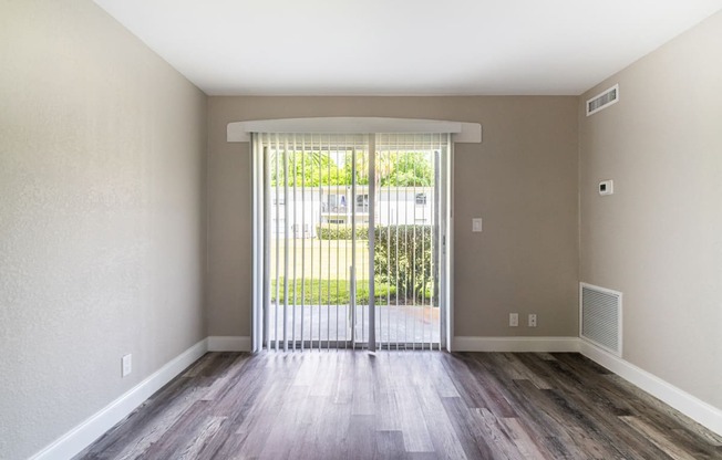 an empty living room with a sliding glass door to a balcony