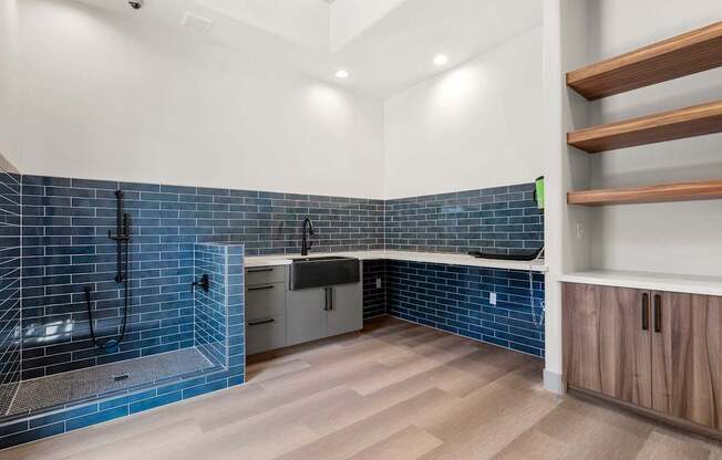 A modern kitchen with a blue tile backsplash and wooden flooring.