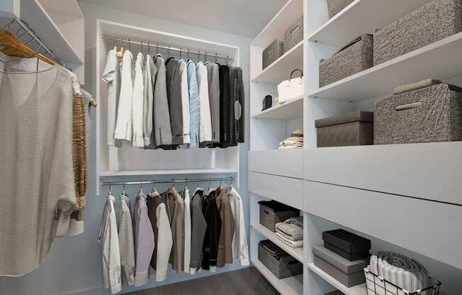 A white closet with clothes hanging and baskets on shelves.