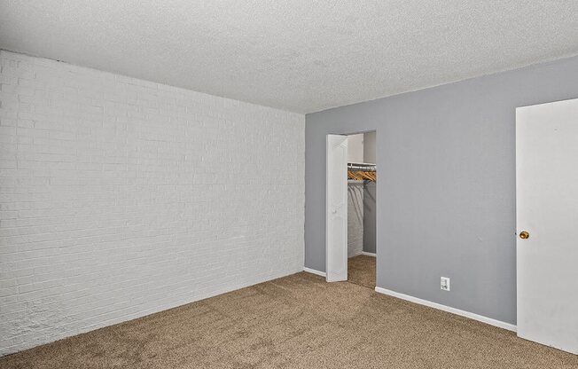 an empty living room with carpet and a hallway to a closet