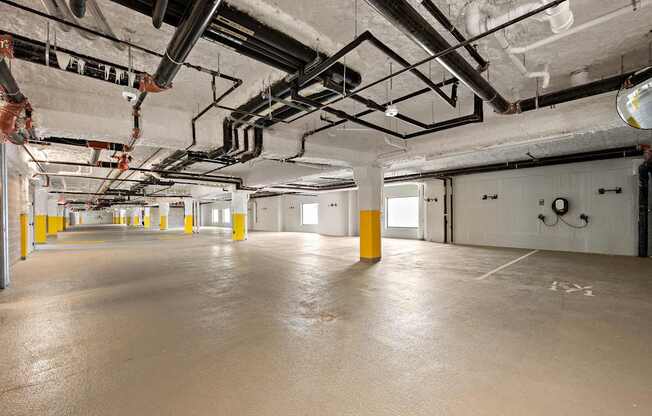 A large, empty warehouse with yellow bollards and exposed pipes.