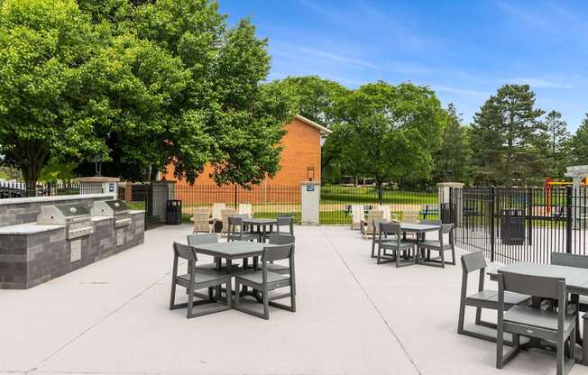 A park with tables and chairs and a fence.