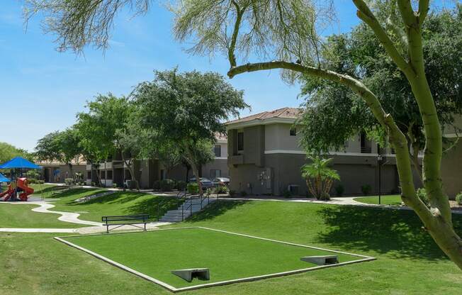 a park with grass and trees in front of apartment buildings