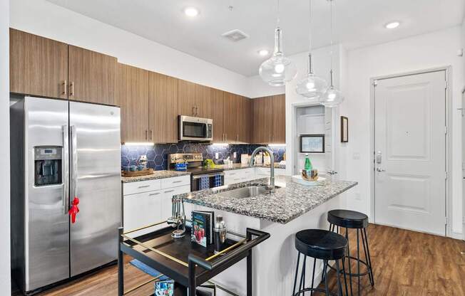 A kitchen with a granite countertop and a stainless steel refrigerator.