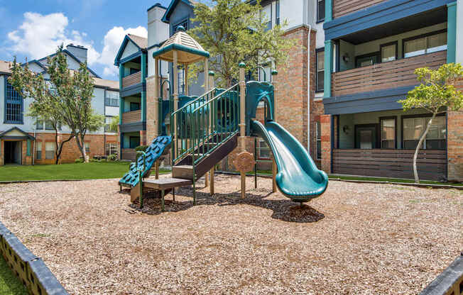 A playground with a green slide and a wooden structure.