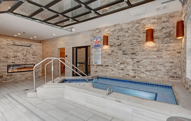 A relaxing spa room here at The Park featuring a soothing hot tub, stone accent walls, modern lighting, and clean tile flooring, creating a calm and inviting wellness space for residents.