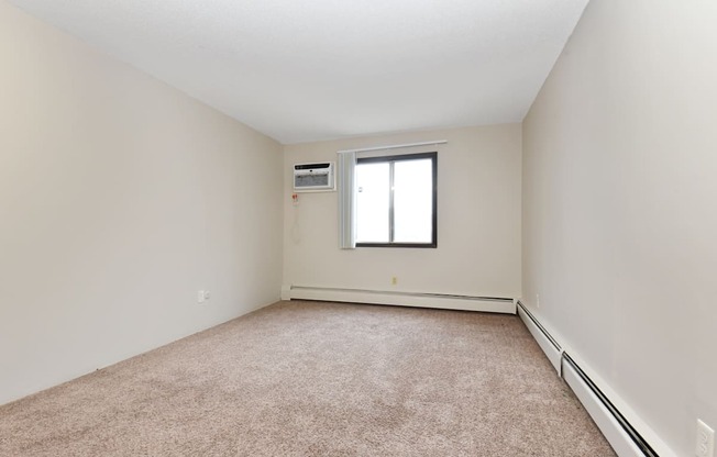 an empty living room with carpet and a window. Roseville, MN Rosedale Estates