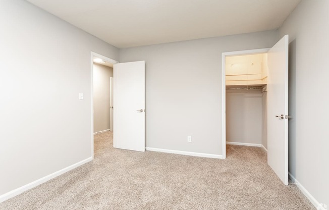 an empty bedroom with two closets and a carpeted floor