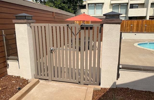 a fence with a red umbrella in front of a pool