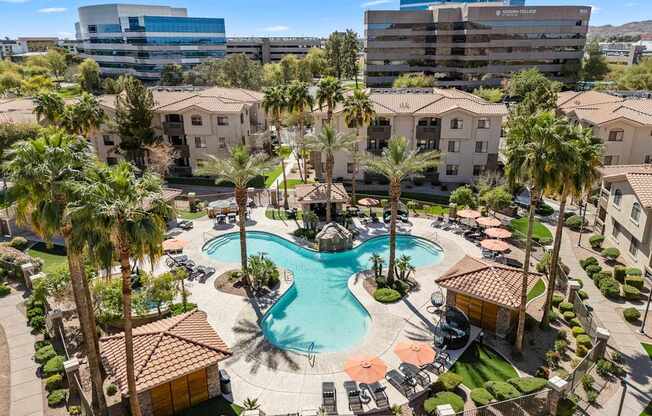 A large swimming pool surrounded by palm trees and buildings.