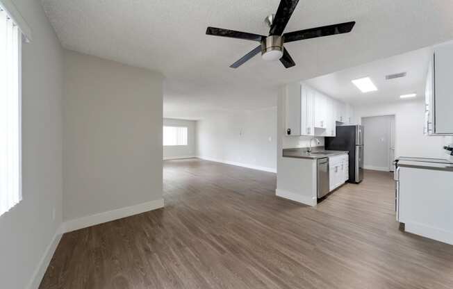 an empty living room and kitchen with a ceiling fan