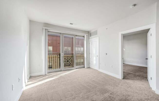 A spacious room with a carpeted floor and a sliding glass door.