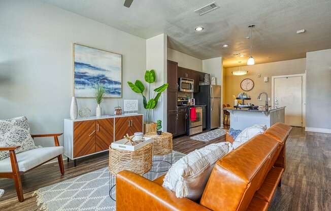A living room with a brown leather couch and a painting on the wall.