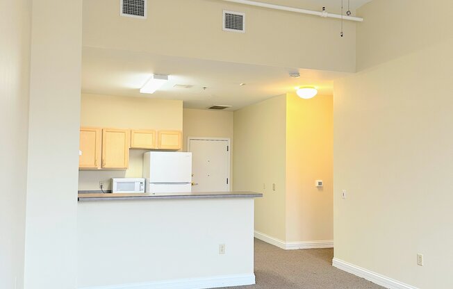 an empty living room and kitchen with a ceiling fan