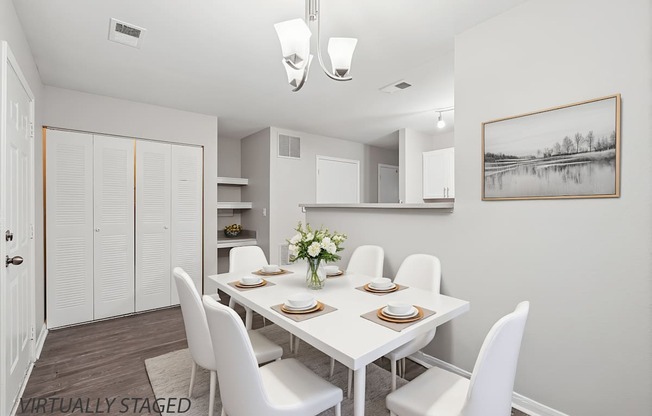 A dining room with a white table and chairs.