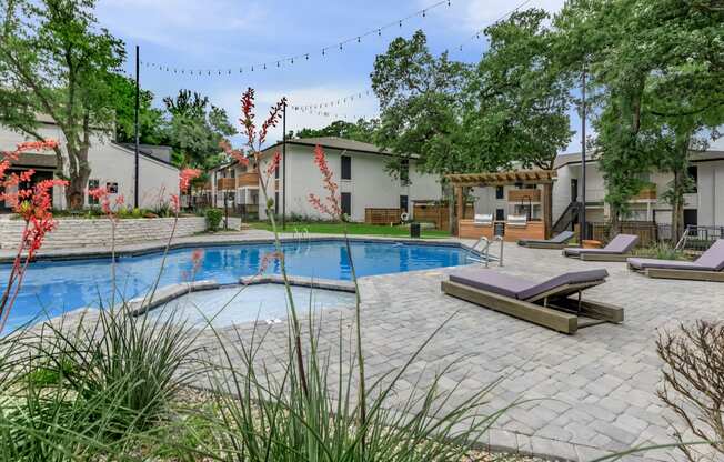 a swimming pool with lounge chairs and trees in the background