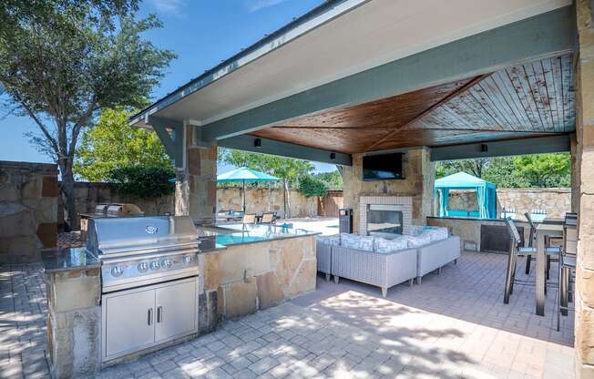 a covered outdoor kitchen with a grill and a pool