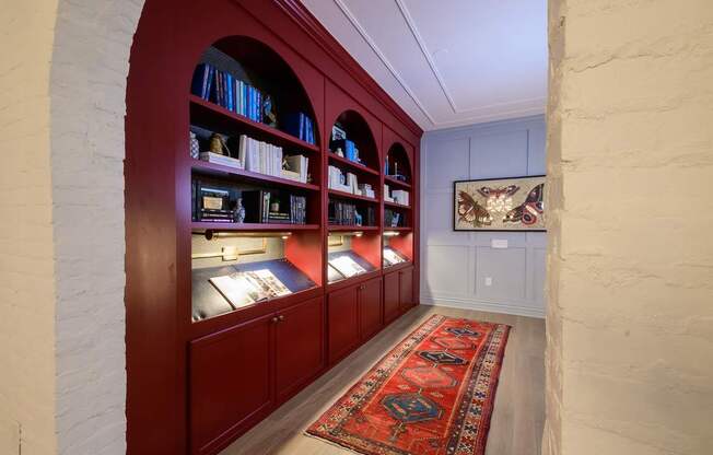 A room with a red carpet and a bookshelf.
