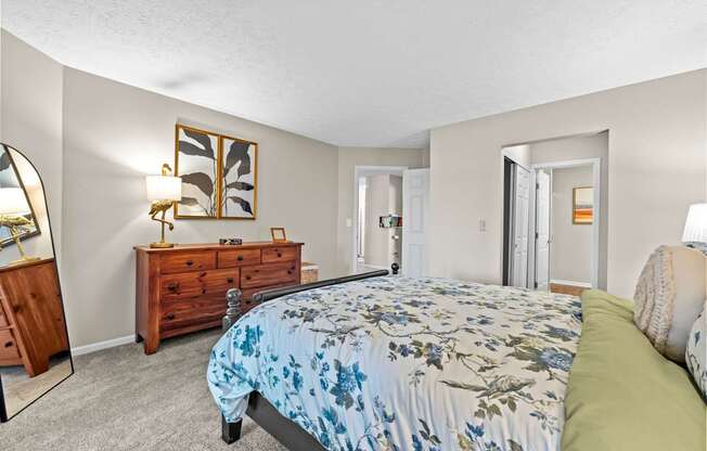 A bedroom with a bed, dresser, mirror, and lamp.