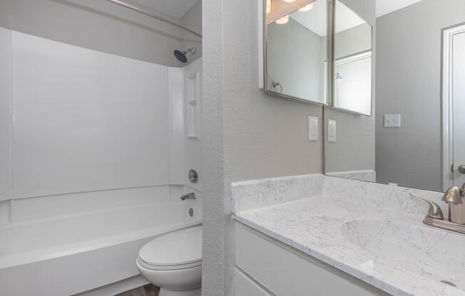 a white sink sitting under a mirror