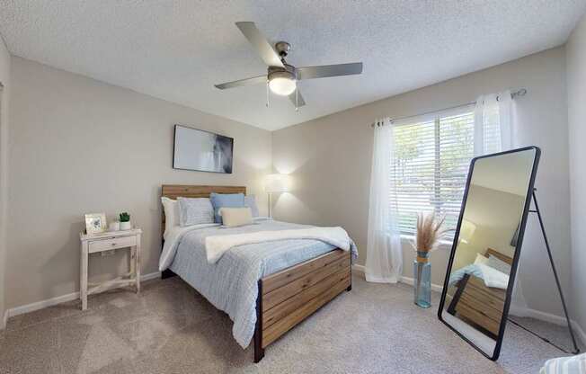 A bedroom with a bed, nightstand, and a ceiling fan.