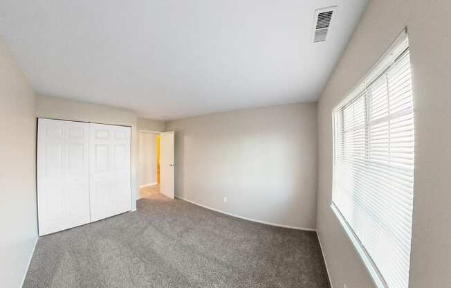 an empty living room with a large window and a white door