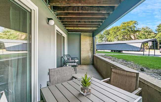 A wooden table with a potted plant on it sits on a patio.