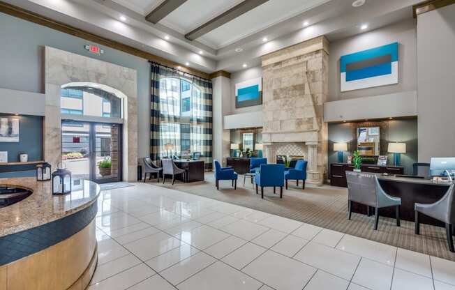 the lobby of a hotel with tables and chairs and a fireplace