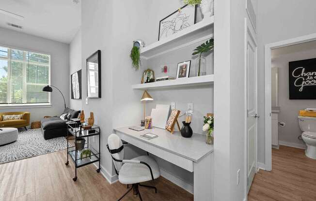 A white desk with a chair and a shelf with green plants on it.