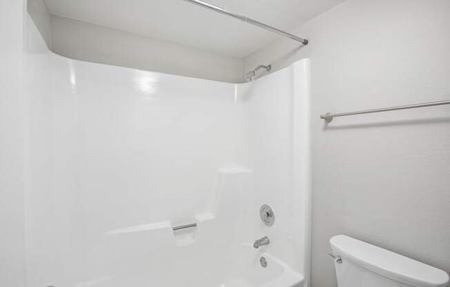 A white bathroom with a tub and toilet.
