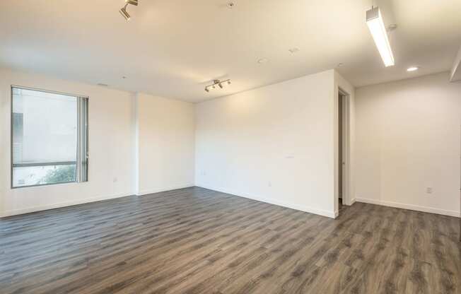 an empty living room with white walls and a window