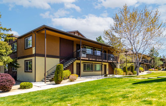 the front of a house with a green lawn and a staircase