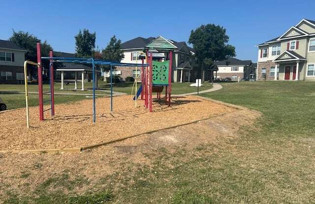 a playground in a park with houses in the background