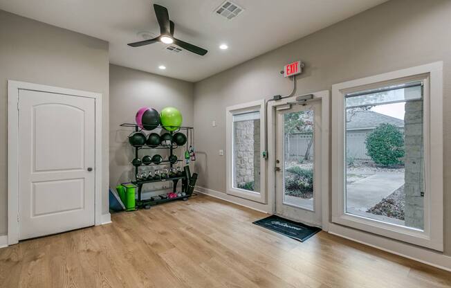 a living room with two windows and a door and a ceiling fan