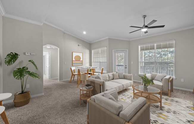 an open living room and dining room with couches and chairs and a ceiling fan