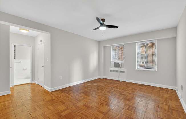 A room with a ceiling fan and wooden flooring.