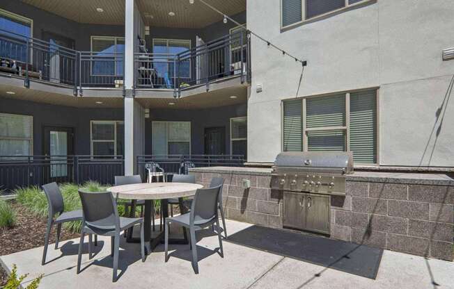 a patio with a table and chairs and a grill at The Flats at Riverwoods, Provo, Utah