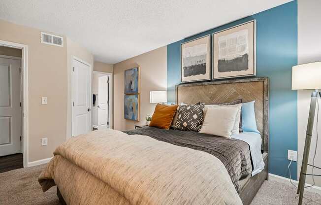 A bedroom with a bed, pillows, and pictures on the wall.