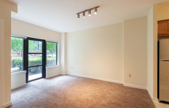 an empty living room with a refrigerator and a window