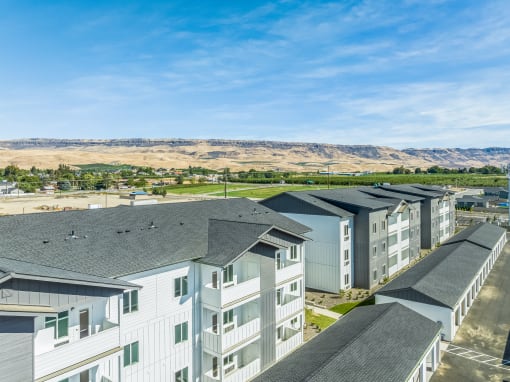 an aerial view of apartment buildings with mountains in the background at Gateway Apartments, East Wenatchee , Washington