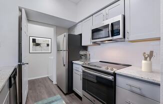 a kitchen with white cabinets and black appliances and a refrigerator