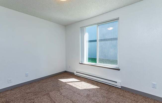 A room with a window and carpeted floor.
