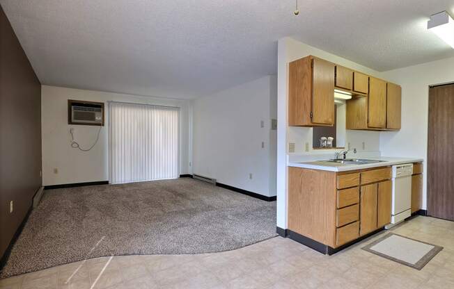 A living room with a glass sliding door with a kitchen. Fargo, ND Prairiewood Meadows