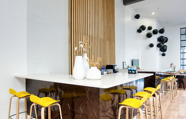 a bar with yellow chairs and a marble counter in a restaurant at Presidio Palms Apartments, Arizona