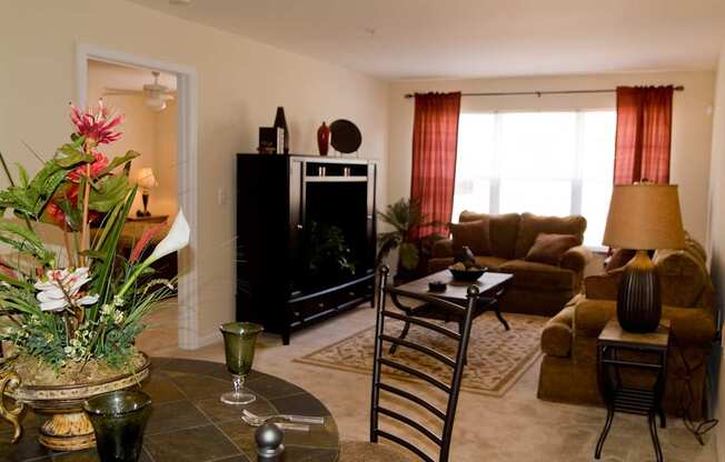 A living room with a fireplace, a couch, a chair, a coffee table, and a vase of flowers.