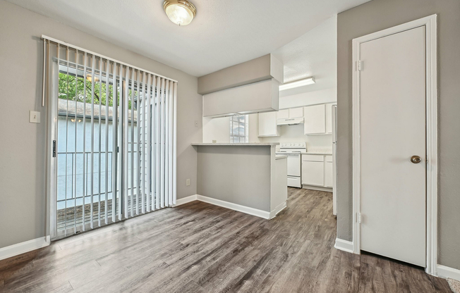 Bright and modern kitchen with sleek white cabinetry, an inviting breakfast bar, and elegant hardwood floors opening to a sunlit patio at Driscoll Place.